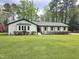 Charming single-story home with white exterior and lush green lawn, enhanced by colorful flowering shrubs at 5920 Holly Dr, Raleigh, NC 27616