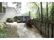 A backyard with a stone patio, a deck, wooden fence, and mature trees offers privacy at 6417 Meadow View Dr, Raleigh, NC 27609