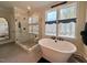 Bright bathroom with a soaking tub under a double window and a glass shower with black fixtures at 6521 Camellia Creek Dr, Raleigh, NC 27603