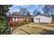 Backyard view with brick house and detached garage with lawn and mature plantings on a sunny day at 706 Forest Dr, Garner, NC 27529