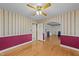 Bedroom featuring hardwood floors, two-tone walls, ceiling fan, and an archway leading to another room at 706 Forest Dr, Garner, NC 27529