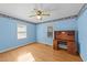 Blue bedroom with hardwood floors, ceiling fan, two windows, and a wooden desk with drawers at 706 Forest Dr, Garner, NC 27529