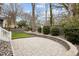 Landscaped backyard featuring a stone patio, mature trees, retaining wall, and a well-maintained wooden fence at 711 Virginia Ave, Raleigh, NC 27604