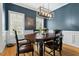 Stylish dining room featuring blue walls, white trim, hardwood floors, and a contemporary chandelier over the table at 7252 Bedford Ridge Dr, Apex, NC 27539