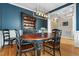 Elegant dining room with dark blue walls, wainscoting, hardwood floors, and a modern chandelier above the table at 7252 Bedford Ridge Dr, Apex, NC 27539
