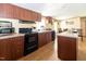 Kitchen with wood cabinets, black appliances, and an island, complemented by wood-look flooring at 8091 Stone Heritage Rd, Middlesex, NC 27557