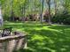 Large backyard with lush green grass, mature trees, and a bricked seating area at 8300 Clarks Branch Dr, Raleigh, NC 27613