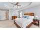 Bright main bedroom with a ceiling fan, tray ceilings, and multiple windows at 8300 Clarks Branch Dr, Raleigh, NC 27613