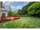 Lush, green backyard featuring a well-maintained lawn, mature trees, and a spacious wooden deck, perfect for entertaining at 9201 Club Hill Dr, Raleigh, NC 27617