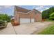 Brick garage with driveway and flower beds, complemented by manicured landscaping adding curb appeal at 9201 Club Hill Dr, Raleigh, NC 27617