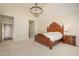 A bright bedroom with a large chandelier, showing neutral walls, plush carpeting, and a decorative, wood bed frame at 9201 Club Hill Dr, Raleigh, NC 27617