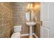 Elegant powder room with pedestal sink, hardwood floors, decorative wallpaper and a well-placed, oval mirror at 9201 Club Hill Dr, Raleigh, NC 27617