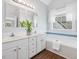 Bright bathroom with double vanity, white cabinets, large soaking tub, and wood look floors at 1008 Brittley Way, Apex, NC 27502
