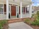 Charming front porch with red brick steps, white columns, and manicured greenery beside the red front door at 1008 Brittley Way, Apex, NC 27502