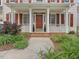 Inviting front porch showcasing a red front door, white columns, and lush landscaping at 1008 Brittley Way, Apex, NC 27502
