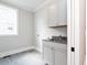 Well-lit laundry room with shaker cabinets, a utility sink, and gray tile flooring at 1029 Azalea Garden Cir, Raleigh, NC 27603