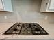 Close-up of a stainless steel gas stove top with stylish tile backsplash and white countertops at 1237 Porters Call Dr, Wendell, NC 27591