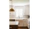 A well-lit kitchen with white cabinets, a farmhouse sink, quartz countertop, and pendant lights at 1326 Apache Ln, Apex, NC 27502