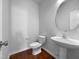 Clean and modern powder room with a pedestal sink, round mirror, and wood-look flooring at 1412 Wesser Ct, Fuquay Varina, NC 27526