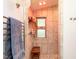 Walk-in shower with floor-to-ceiling tile, a glass shelf, and a charming window at 1604 Meadow Ln, Chapel Hill, NC 27516