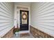 Inviting front door with a decorative wreath, colorful rug, and flower pot accents at 184 Wildfell Trl, Cary, NC 27513