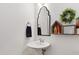 Stylish powder room boasts a sleek pedestal sink and decorative mirror with charming accent wreath at 184 Wildfell Trl, Cary, NC 27513
