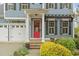 Home featuring a bright red front door, black shutters, and a three-car garage on a sunny day at 200 Windy Knoll Cir, Chapel Hill, NC 27516