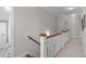 Well-lit hallway featuring a wooden railing, carpeted floors, and neutral paint at 200 Windy Knoll Cir, Chapel Hill, NC 27516
