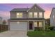 Charming two-story home with a two-car garage, stone accents, and a well-manicured lawn during a lovely dusk at 205 Loxton St, Fuquay Varina, NC 27526