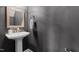 Modern powder room featuring a pedestal sink, gold mirror, and gray walls at 2101 Piney Brook Rd # 105, Raleigh, NC 27614