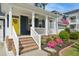 Inviting front porch with white railings, brick stairs, colorful landscaping, and an American flag at 2308 Swansea Ln, Apex, NC 27502