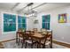 Well-lit dining room with a wooden table, modern light fixture, and windows offering green views at 3217 Brennan Dr, Raleigh, NC 27613