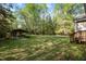 Spacious backyard featuring a well-maintained lawn, a shed and the home's rear exterior, and lush trees at 359 Punch Hill Farm Rd, Rougemont, NC 27572