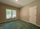 Cozy bedroom featuring neutral walls, green carpet, a window with blinds, and a white door at 359 Punch Hill Farm Rd, Rougemont, NC 27572