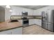 Modern kitchen featuring stainless steel appliances, white cabinets, and wood-look flooring at 359 Punch Hill Farm Rd, Rougemont, NC 27572