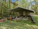 Exterior of an outbuilding, with a gravel floor and covered parking, surrounded by lush greenery at 359 Punch Hill Farm Rd, Rougemont, NC 27572