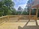 Exterior view of new wooden deck with wooden railings, overlooking lush trees and a small lake on a sunny day at 42 Ponchartrain St, Fuquay Varina, NC 27526