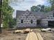 New construction with dark roof, wrapped in house wrap, surrounded by tall trees and a lake in the background at 42 Ponchartrain St, Fuquay Varina, NC 27526