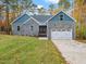 Charming home boasts a stone facade, blue accents, an attached two-car garage, and a well-manicured lawn at 42 Ponchartrain St, Fuquay Varina, NC 27526