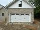 Exterior view of a new home's garage showcasing its stylish white door and stone facade at 42 Ponchartrain St, Fuquay Varina, NC 27526