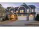 Charming two-story home with a three-car garage and manicured front yard at dusk at 437 Creekhurst Pl, Cary, NC 27519