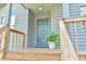 A welcoming blue front door with wooden railing and a potted fern, offering a cozy entrance at 505 Marion Way, Chapel Hill, NC 27516