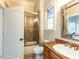 Well-lit bathroom featuring a glass-enclosed shower, toilet, and vanity with elegant mirror at 5768 Cavanaugh Dr, Raleigh, NC 27614