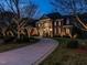 Elegant brick home illuminated at twilight, showcasing its circular drive and professionally landscaped yard at 5768 Cavanaugh Dr, Raleigh, NC 27614