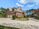 Exterior showcasing three-car garage, brick facade, manicured landscaping, and circular driveway at 5768 Cavanaugh Dr, Raleigh, NC 27614