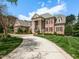 Stately brick home with grand columns, a circular driveway, and a well-manicured lawn at 5768 Cavanaugh Dr, Raleigh, NC 27614