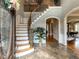 Grand foyer features a curved staircase, marble floors, and arched doorways at 5768 Cavanaugh Dr, Raleigh, NC 27614