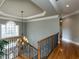 Elegant hallway featuring hardwood floors, decorative railing, chandelier, and arched window offering natural light at 5768 Cavanaugh Dr, Raleigh, NC 27614