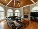 The living room features a stone fireplace, wood ceiling, large leather sectional and many windows at 5768 Cavanaugh Dr, Raleigh, NC 27614