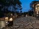 Nighttime view of the outdoor living space with stone patio, outdoor kitchen, grill, and fire pit at 5768 Cavanaugh Dr, Raleigh, NC 27614